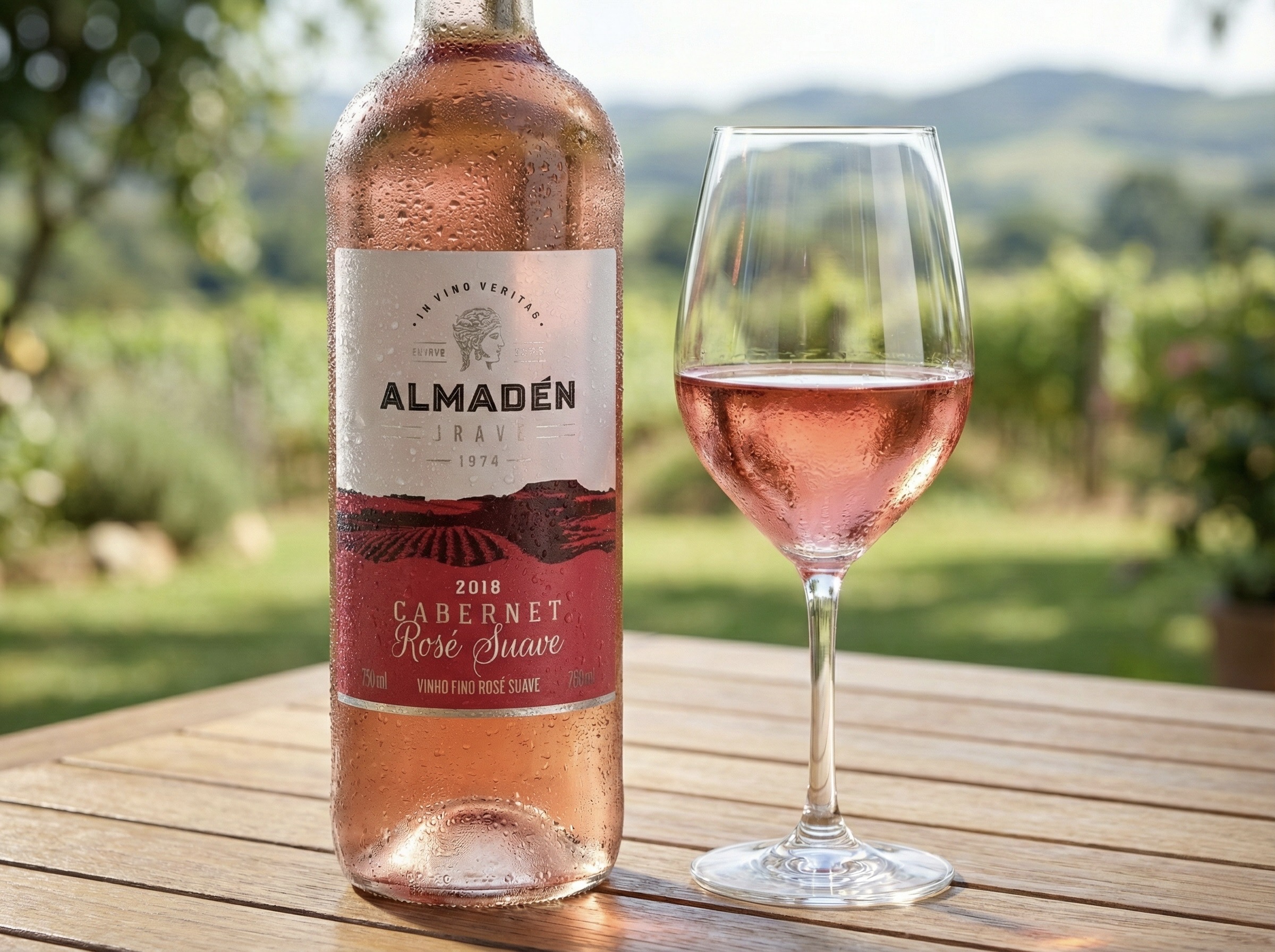 Taça e garrafa de vinho rose almaden gelado sobre uma mesa de madeira ao ar livre.
