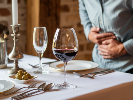 Pessoa com desconforto abdominal após consumir vinho, ilustrando o tema vinho causa diarreia.